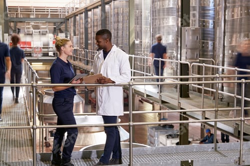 Vista previa: Dos empleados hablando de cerca en una moderna fábrica de vino