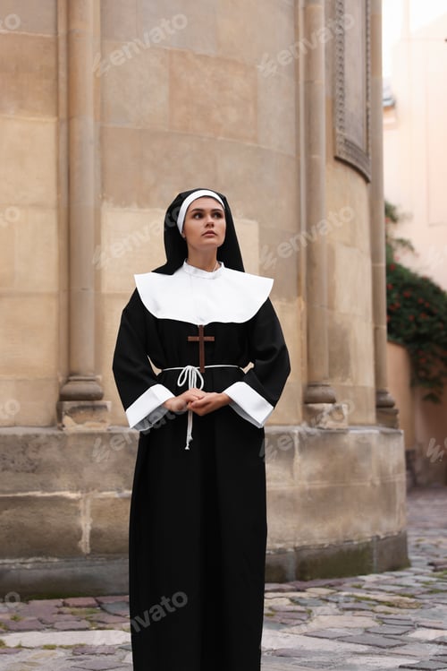 Preview: Young nun with Christian cross near building outdoors
