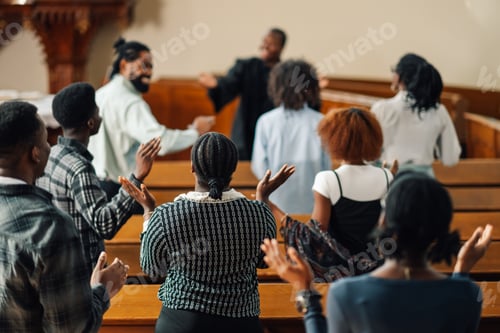 Preview: Group of people raising their hands while praying inside the church