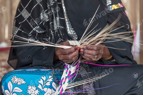 Preview: Emirati woman is weaving traditional basket from palm leaves, slow shutter speed to show the motion