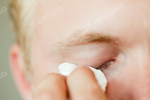 Preview: Closeup of a person wiping away tears or applying eye makeup.