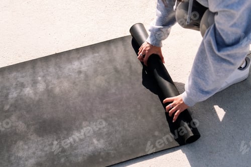 Preview: hands of a young woman rolling a yoga mat