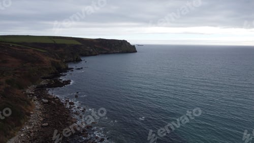 Vista previa: Rocky coastline with cliffs and the ocean under a cloudy sky