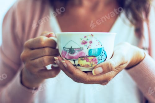 Preview: Woman holding a cup of coffee with her hands