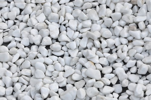Preview: A lot of round and oval stones of white color lie on the ground in the garden