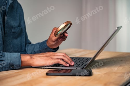 Preview: A man in a purposeful business pose holds a magnifier over a laptop, a hand gesture and intense