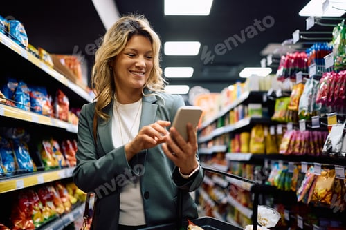 Preview: Happy woman using mobile phone in supermarket.