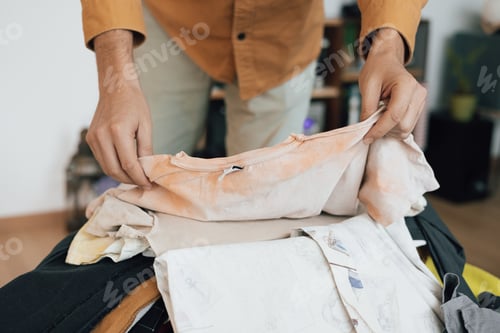 Preview: Close up of young man's hands folding clothes after washing