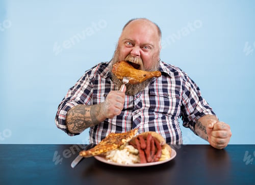 Preview: Funny man with overweight eats smoked chicken leg at table on light blue background