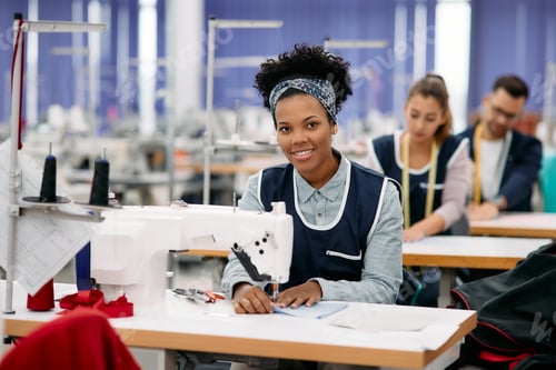 Preview: Happy African American woman working as seamstress in clothing factory.