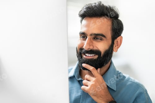 Preview: Happy indian businessman working on computer in office, looking at monitor and smiling, touching