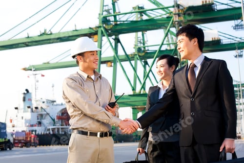 Preview: businesspeople and a shipping industry worker shaking hands at a shipping port