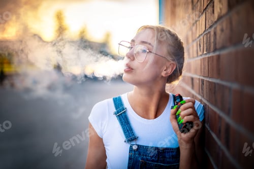 Preview: Modern girl outdoor smoking vaping electronic cigarette making big smoke cloud