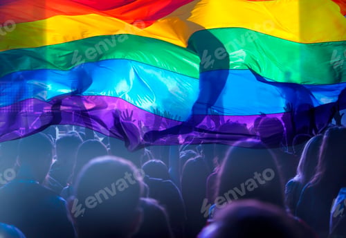 Preview: Colorful LGBT flag blows in the breez over crowd.