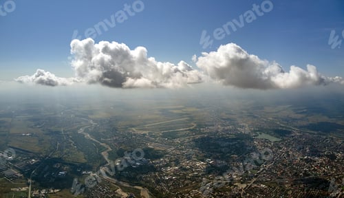 Preview: Aerial view from airplane window at high altitude of distant city covered with white puffy cumulus