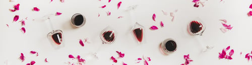 Preview: Glasses with red wine and pink flowers, wide composition