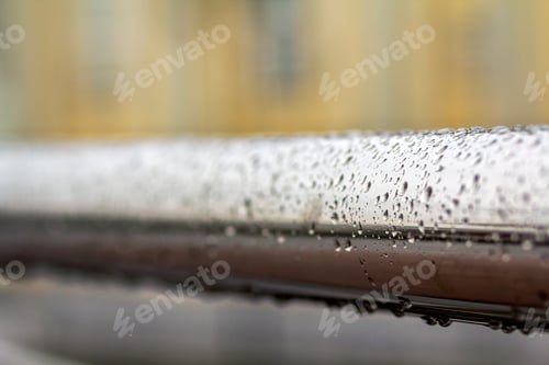 Preview: Close-up of horizontal metal wet shiny pipe with big rain water