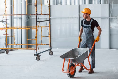 Preview: Walks with wheelbarrows. Man in grey uniform works indoors in modern big office at daytime