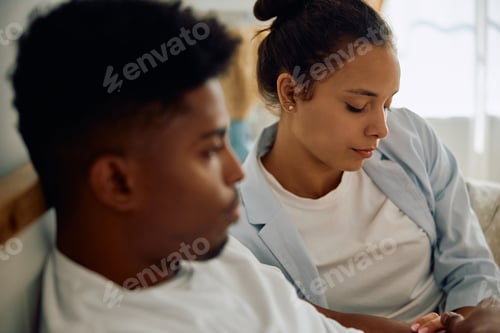 Preview: Sad Hispanic woman and her boyfriend in bedroom.