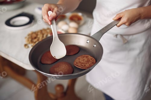 Preview: Chef is frying chocolate pancakes in a pan.