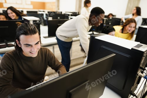 Preview: Young multiracial students using computers during business class at school - Focus on left guy face