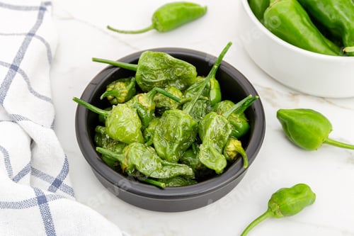 Preview: Cooked Padron peppers in a a bowl on marble table