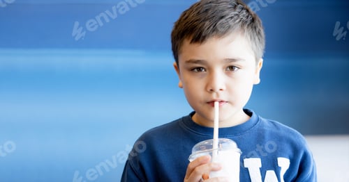 Preview: Kid Drinking Healthy Juice,Cute boy using straw drinking summer fruit smoothie from plastic glass