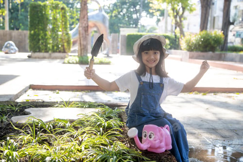 Preview: Asian little child girl pouring water on the trees. kid helps to care for the plants