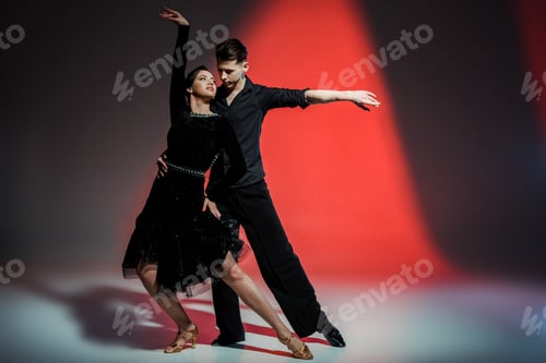 Preview: elegant young couple of ballroom dancers dancing in red light