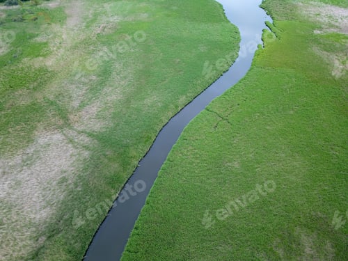 Preview: Aerial view of a narrow river winding through a lush green wetland.