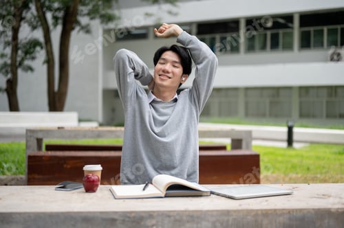 Preview: A happy and relaxed Asian male student is stretching his arms, feeling carefree and comfortable