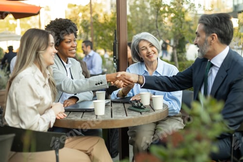 Preview: Business people shaking hands during a meeting at outdoor cafe