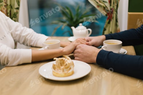 Preview: Romantic Couple Holding Hands Over Tea and Dessert