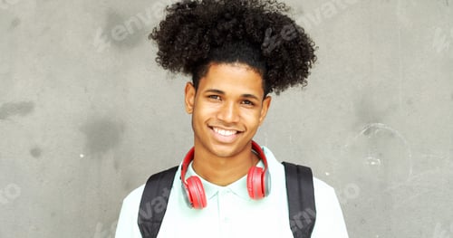 Preview: Smiling afro teen student boy with headphones and afro hair looking at camera