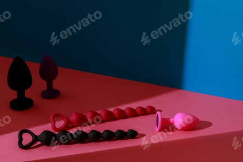 Preview: Different buttplugs and dildos for anal sex on colored background with shadows. Sex shop concept