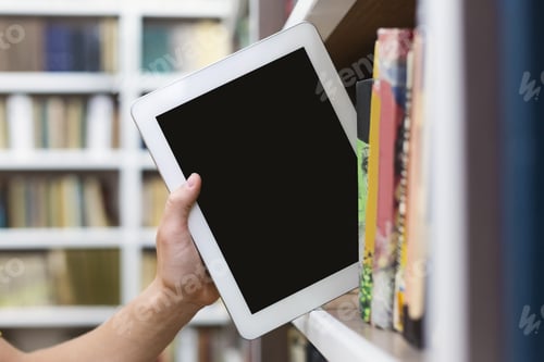 Preview: Caucasian student putting digital tablet on bookshelf