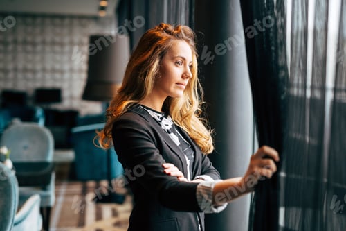 Preview: Pensive beautiful businesswoman looking through window
