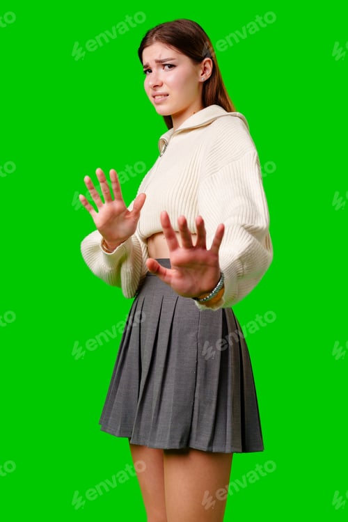 Preview: Young Woman Gesturing Stop With Both Hands Against a Green Background