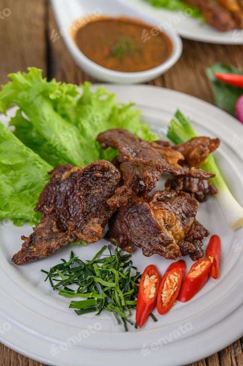 Preview: Beef fried Thai food on a white plate with spring onion, kaffir lime leaves, chilies, salad.