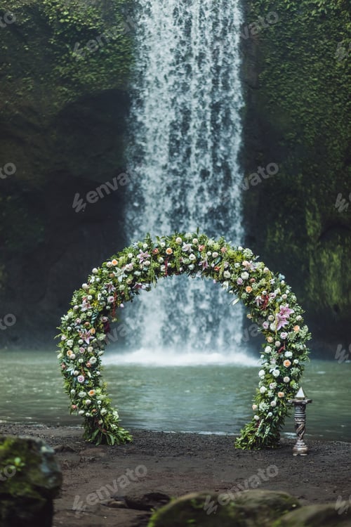 Preview: Wedding ceremony on Tibumana waterfall, Bali. Round arch with fresh flowers in jungle.