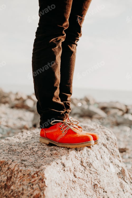 Preview: Woman in casual orange shoes and denim standing on stone in summer day. Fashion concept.