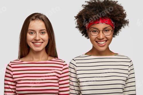 Preview: Photo of satisfied multiethnic women in striped sweaters, have pleasant smiles on faces, model again