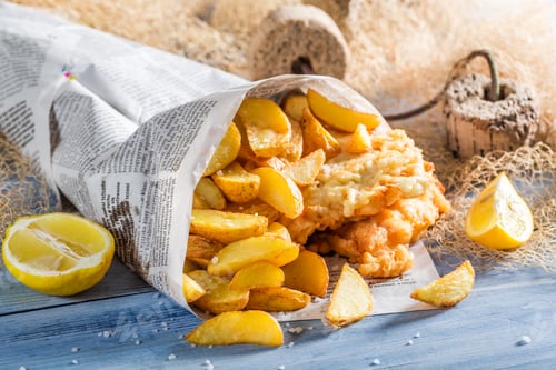 Preview: Homemade fish and chips in newspaper on old wooden table