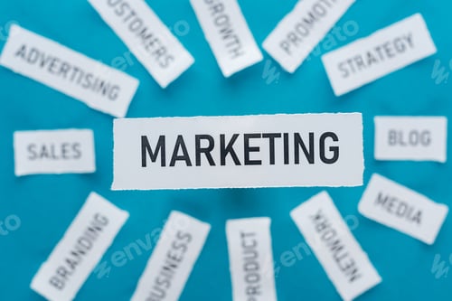 Preview: selective focus of word marketing and components related to marketing on pieces of paper on blue