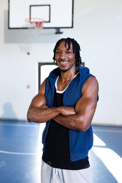 Preview: Standing confidently, basketball player in gym crossing arms and smiling