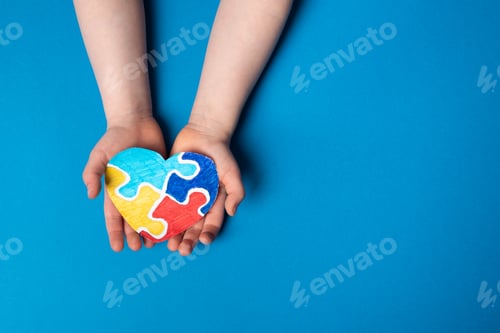 Preview: Child hands holding a puzzle heart on a blue background