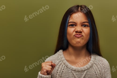 Preview: Portrait of angry and stylish preteen girl with dyed hair wearing knitted sweater while looking