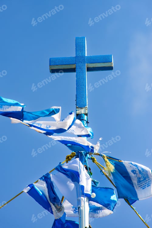 Preview: A striking blue cross, covered in glittering material, stands tall against a clear blue sky