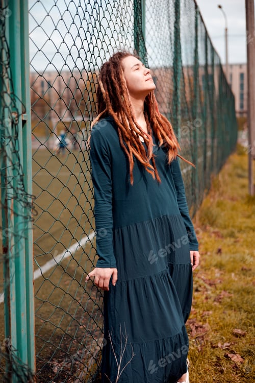 Preview: beautiful girl hipster with dreadlocks outdoors wearing trendy green long dress.