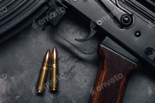 Preview: Two bullets and Kalashnikov assault rifle on gray concrete background, top view
